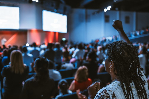 a woman with a raised hand at the back of the audience trying to create effective presentation