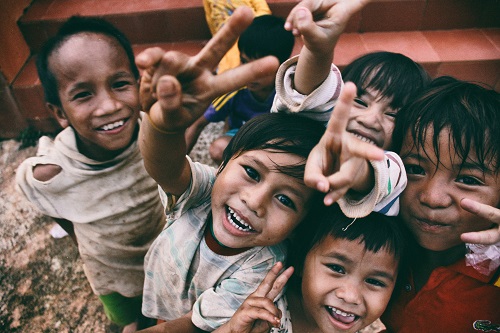 children smiling and making a victory symbol with their fingers to show types of communication