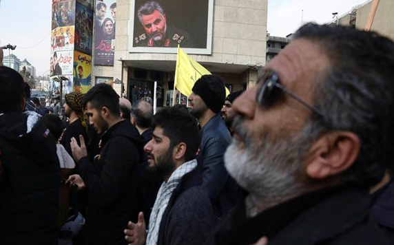 Drone Strike by the US military in Baghdad—Iran’s General Suleimani Killed 2 many men standing in a praying pose side-wise, and some portraits in front displaying a soldier