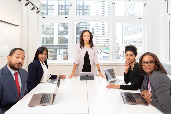 woman standing on the center table with four people on chairs and selecting topics for presentation