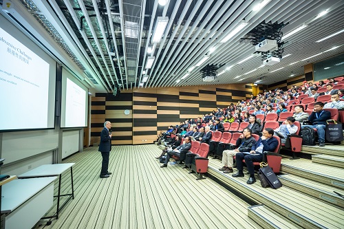 man standing in front of people sitting on red chairs discussing barriers in speaking English