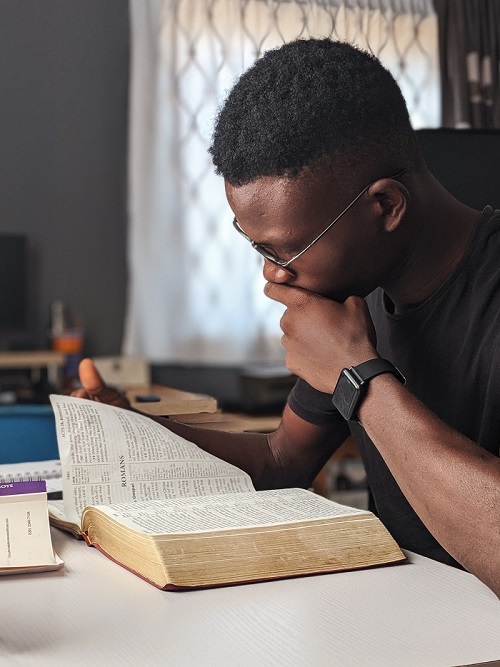 man wearing black crew neck shirt reading book for improving reading skills