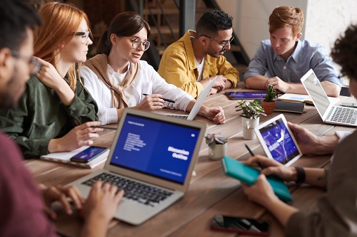 people leaning on wooden table to discuss communication skills for workplace success