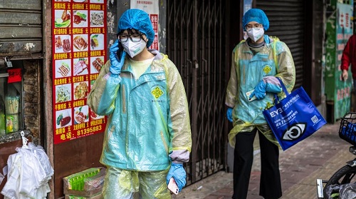 two doctors in blue walking in front of a shop after the coronavirus impact on world economy