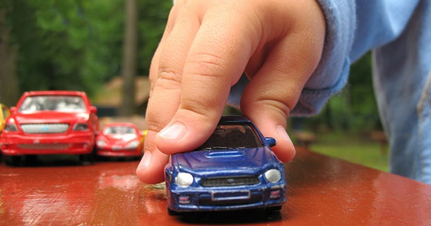 Six Types of Car Insurance Coverage 1 childs-hand-playing with toy cars showing six types of care insurance coverage