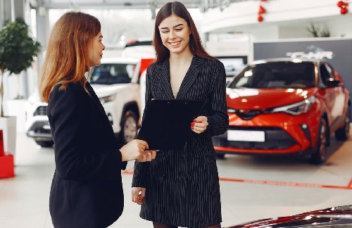 two girls with a red care behind them planning what should you look for when shopping for car insurance