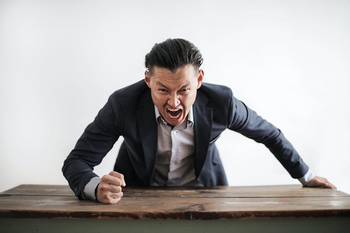 a man in black punching on the table to show negative news response