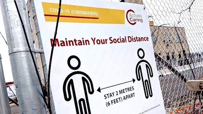 Maintain your social distance on a white and yellow banner for canadian construction trends