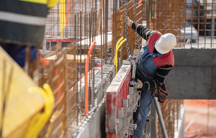 a man iin red coat and white cap showing canadian construction trends